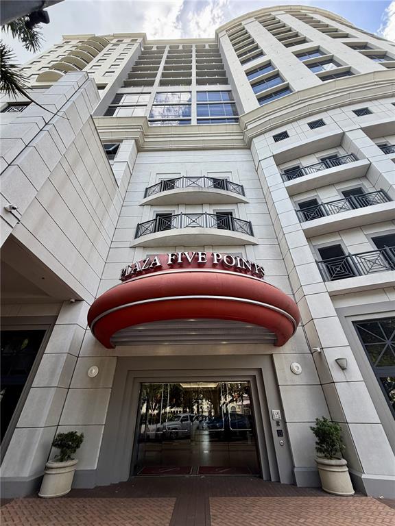 A low-angle exterior view of the Plaza Five Points building entrance with a red awning — 50 CENTRAL AVENUE UNIT 970, SARASOTA, FL