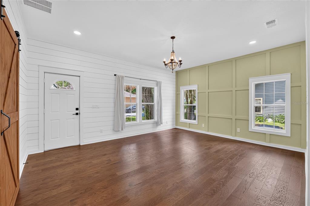A living room features white shiplap walls, a green paneled accent wall, and hardwood floors — 220 NE 1ST AVENUE, WILLISTON, FL