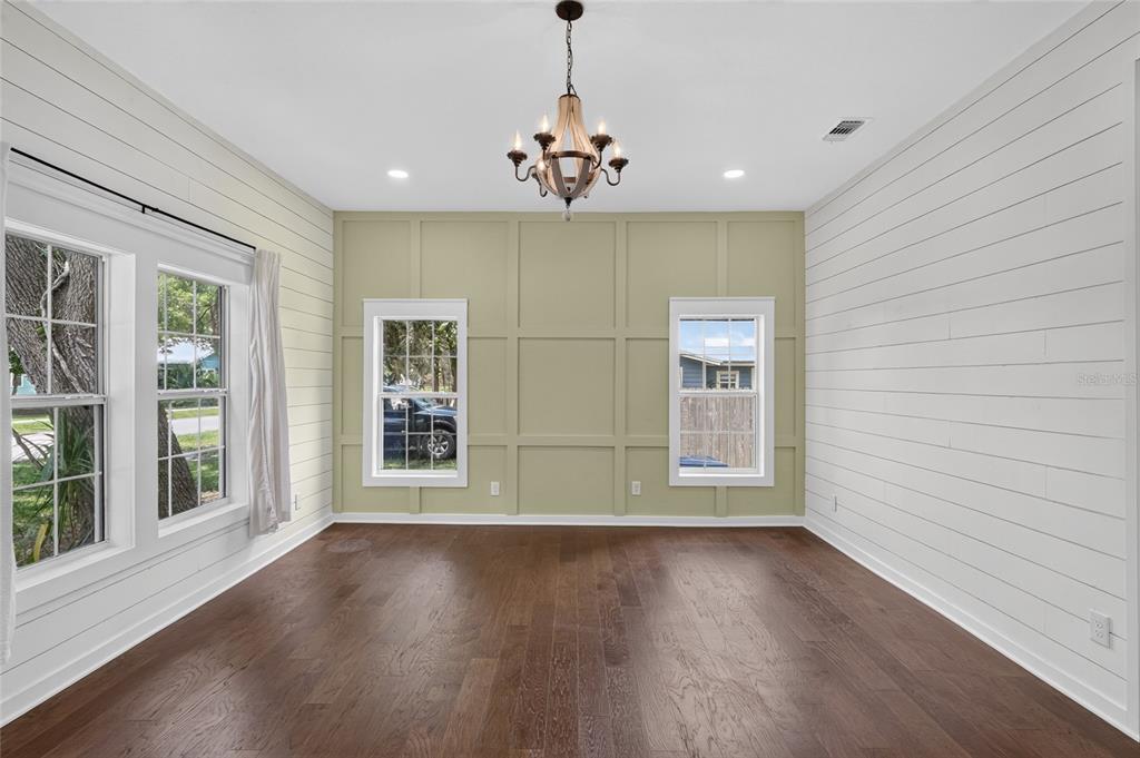 A room with white shiplap walls, a green paneled accent wall, and dark hardwood floors — 220 NE 1ST AVENUE, WILLISTON, FL