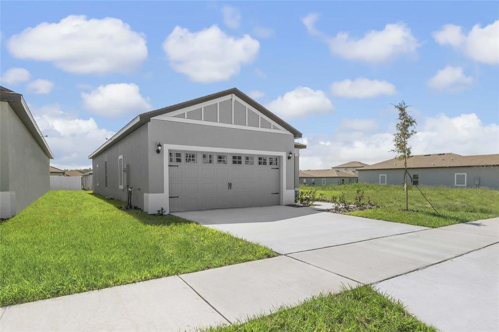 A gray single-story house exterior features a two-car garage and a concrete driveway — 3621 AMANATSU AVENUE, LAKE ALFRED, FL