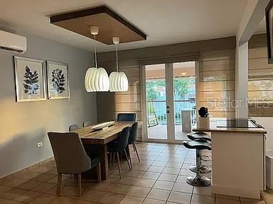 A dining room with a wooden table, pendant lights, and an adjacent kitchen counter — 180 HARBOUR DRIVE UNIT 62D, HUMACAO, PR