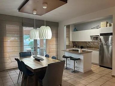 A dining area with a wooden table and pendant lights opens into a modern kitchen — 180 HARBOUR DRIVE UNIT 62D, HUMACAO, PR