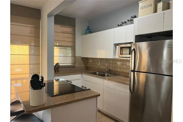 A kitchen features white cabinets, granite countertops, stainless steel appliances, and a small island — 180 HARBOUR DRIVE UNIT 62D, HUMACAO, PR