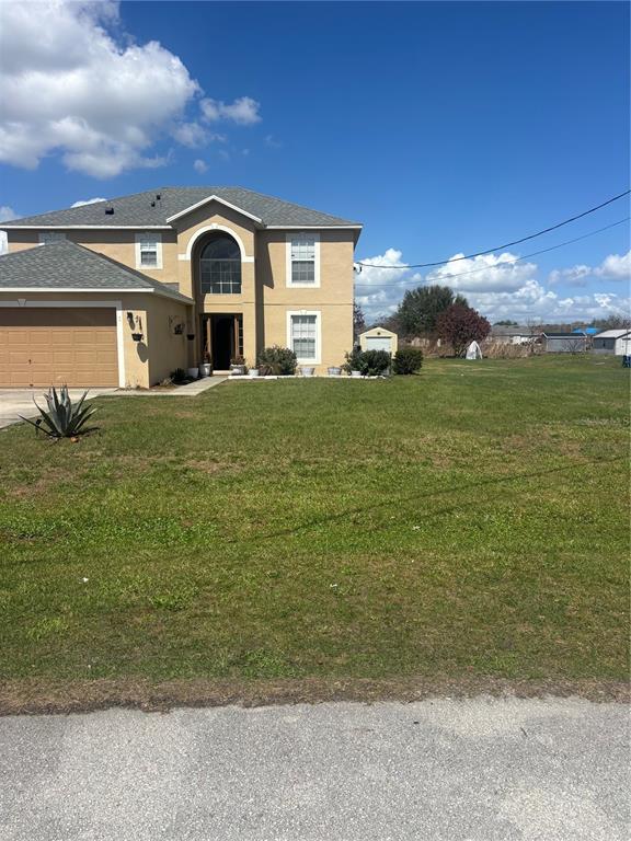 A two-story tan house with a garage and a large front yard under a blue sky — 335 COLUMBO STREET, WINTER HAVEN, FL