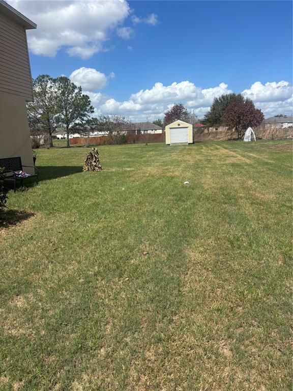 A large, grassy backyard features a small storage shed and a pile of firewood — 335 COLUMBO STREET, WINTER HAVEN, FL