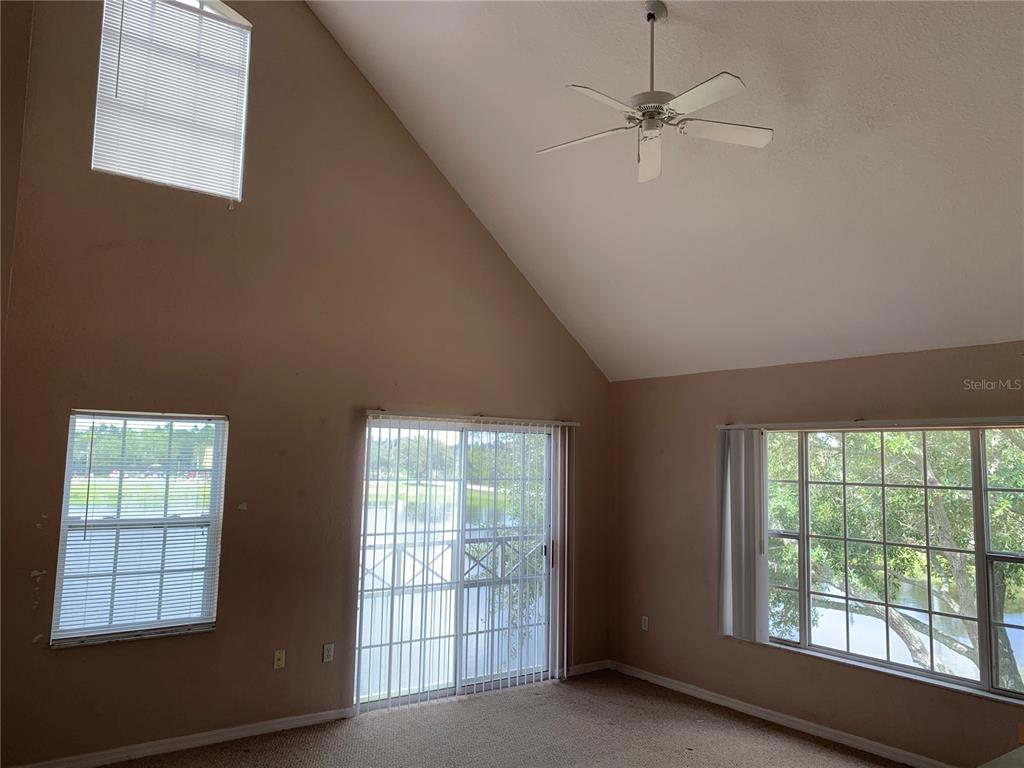 An open living area features wood-look flooring, a vaulted ceiling, and a staircase leading down — 9832 LAKE CHASE ISLAND WAY, TAMPA, FL