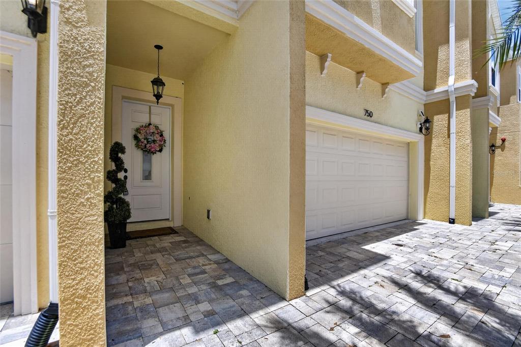 The exterior of a yellow townhouse features a paved driveway, a garage, and a covered entryway — 750 GRAND CYPRESS LANE, TARPON SPRINGS, FL