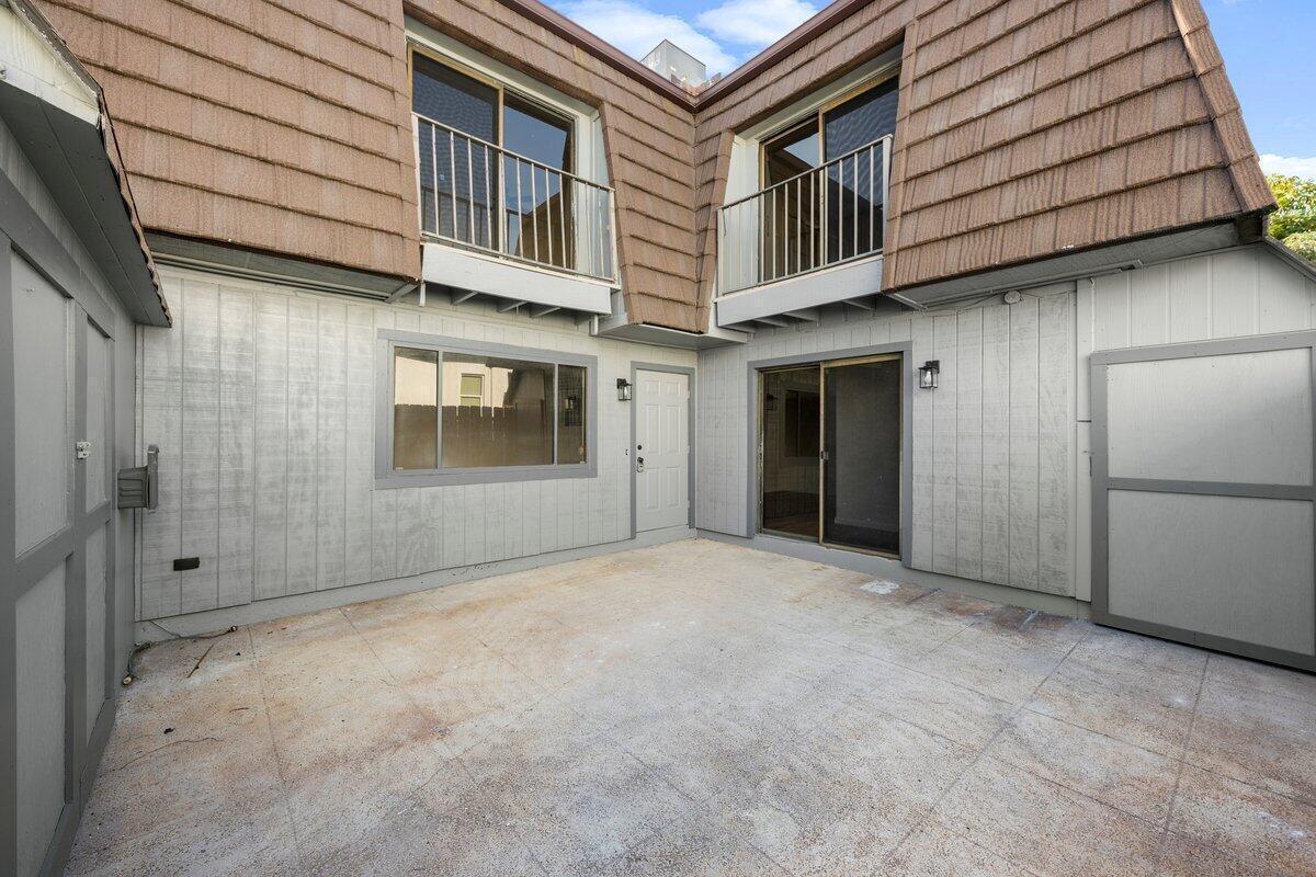 A concrete patio sits between the two-story exterior walls of a residential building — 1980 NE Dixie Highway, Jensen Beach FL 34957, JENSEN BEACH, FL