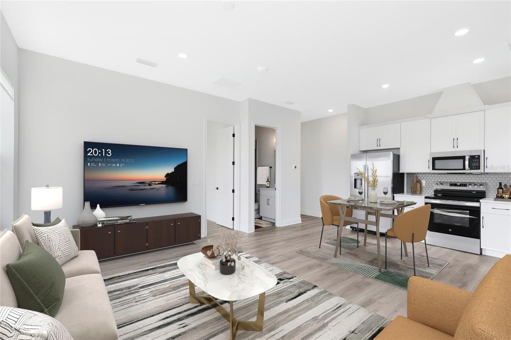 A living room and kitchen area with light wood floors, white cabinets, and modern furniture — 10105 HASSELMANN ALLEY, ORLANDO, FL