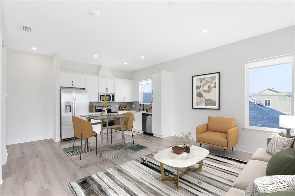 An open-concept kitchen and living area with light wood floors, white cabinetry, and modern furniture — 10105 HASSELMANN ALLEY, ORLANDO, FL