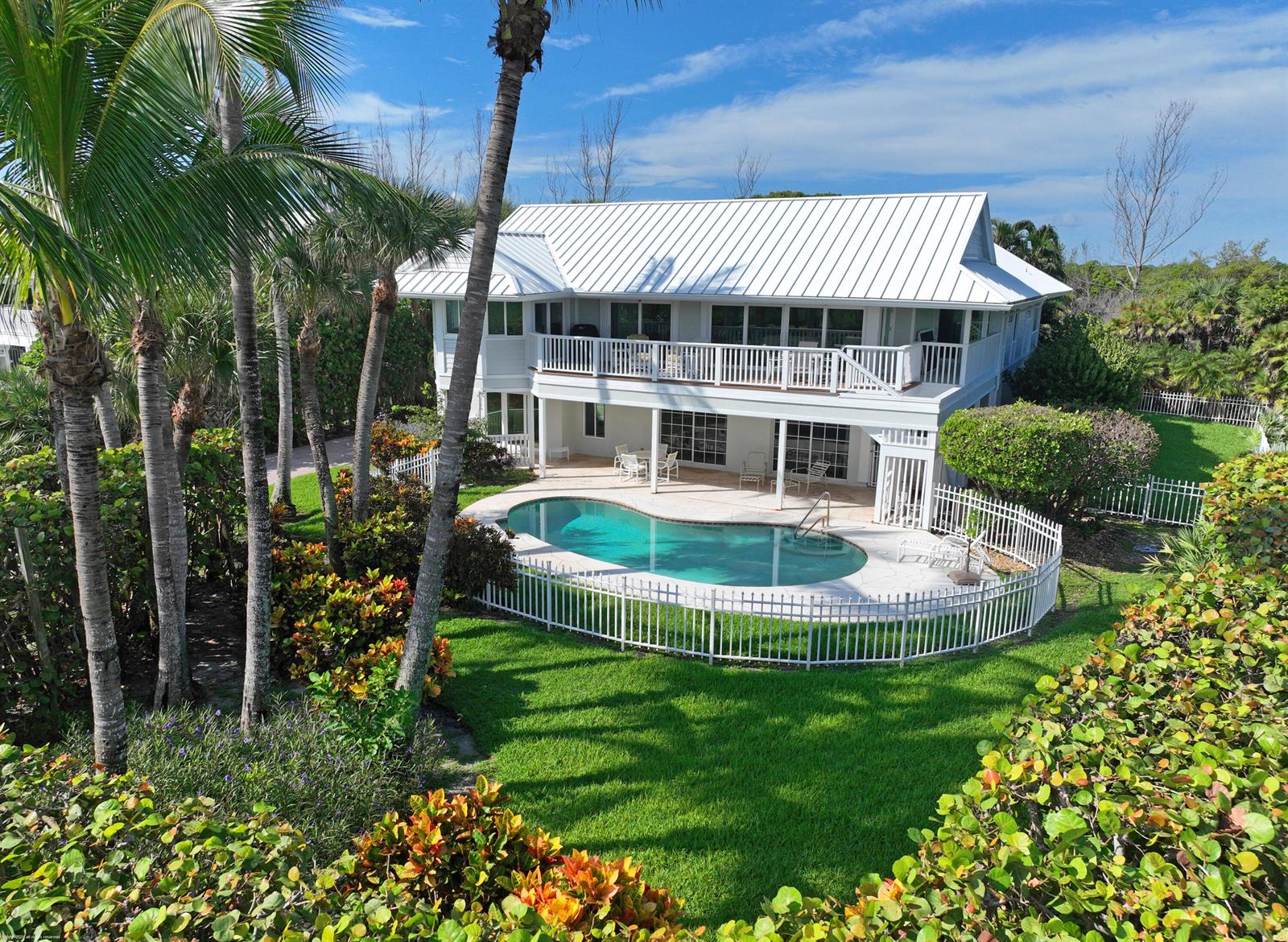 An elevated view of a two-story house with a white metal roof and backyard pool — 162 N Beach Road, Jupiter Island FL 33455, JUPITER ISLAND, FL