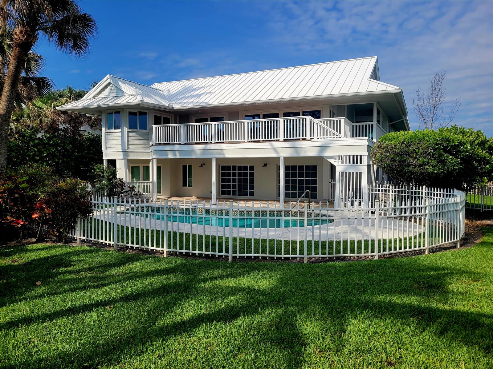A two-story house with a white metal roof, a balcony, and a fenced-in backyard pool — 162 N Beach Road, Jupiter Island FL 33455, JUPITER ISLAND, FL