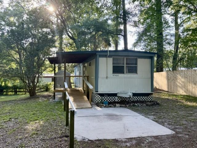 A single-wide mobile home with a wooden ramp and a concrete pad sits outdoors — 18400 NW 233RD TERRACE, HIGH SPRINGS, FL
