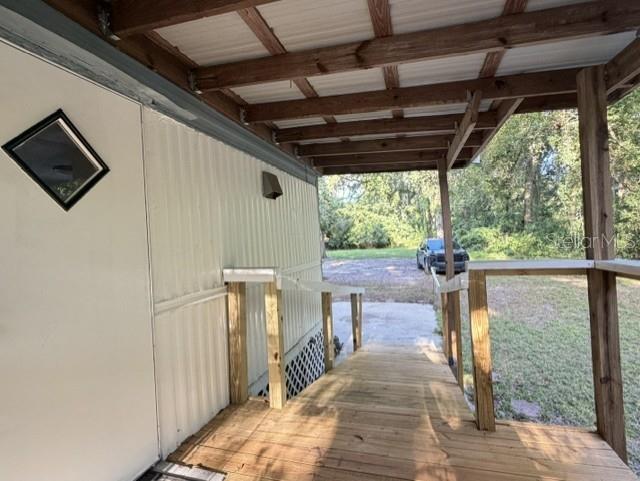 A wooden ramp leads to the side entrance of a mobile home with a covered porch — 18400 NW 233RD TERRACE, HIGH SPRINGS, FL