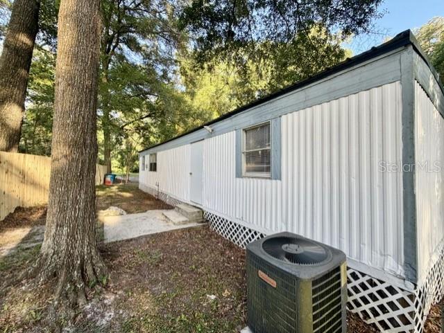 The exterior of a mobile home features white vertical siding, a window, and an air conditioner — 18400 NW 233RD TERRACE, HIGH SPRINGS, FL