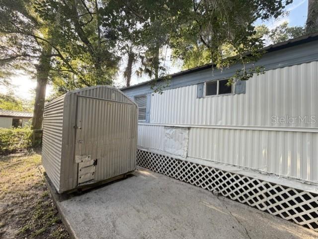 A metal storage shed sits on a concrete pad next to a mobile home exterior — 18400 NW 233RD TERRACE, HIGH SPRINGS, FL