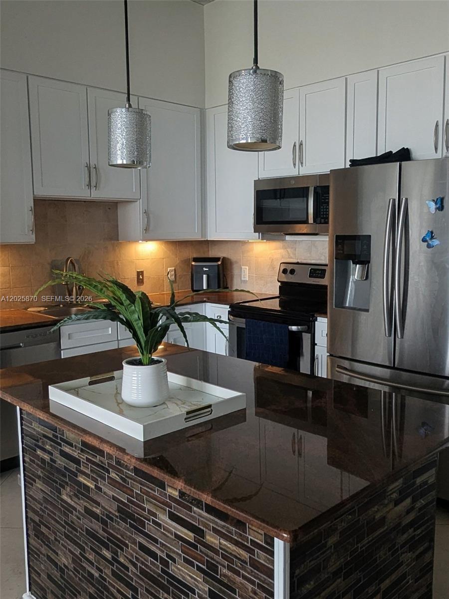 A kitchen features white cabinetry, stainless steel appliances, and a dark granite-topped island — 2001 Biscayne Blvd # 3506, Miami FL 33137, MIAMI, FL