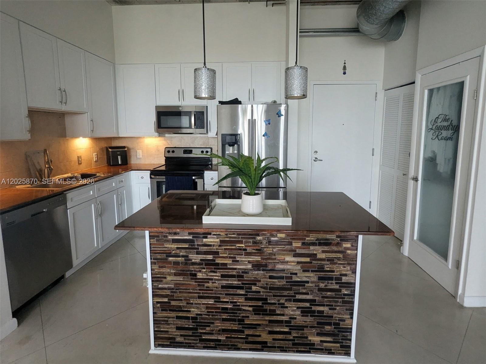 A kitchen features white cabinets, stainless steel appliances, and a tiled island with a dark countertop — 2001 Biscayne Blvd # 3506, Miami FL 33137, MIAMI, FL