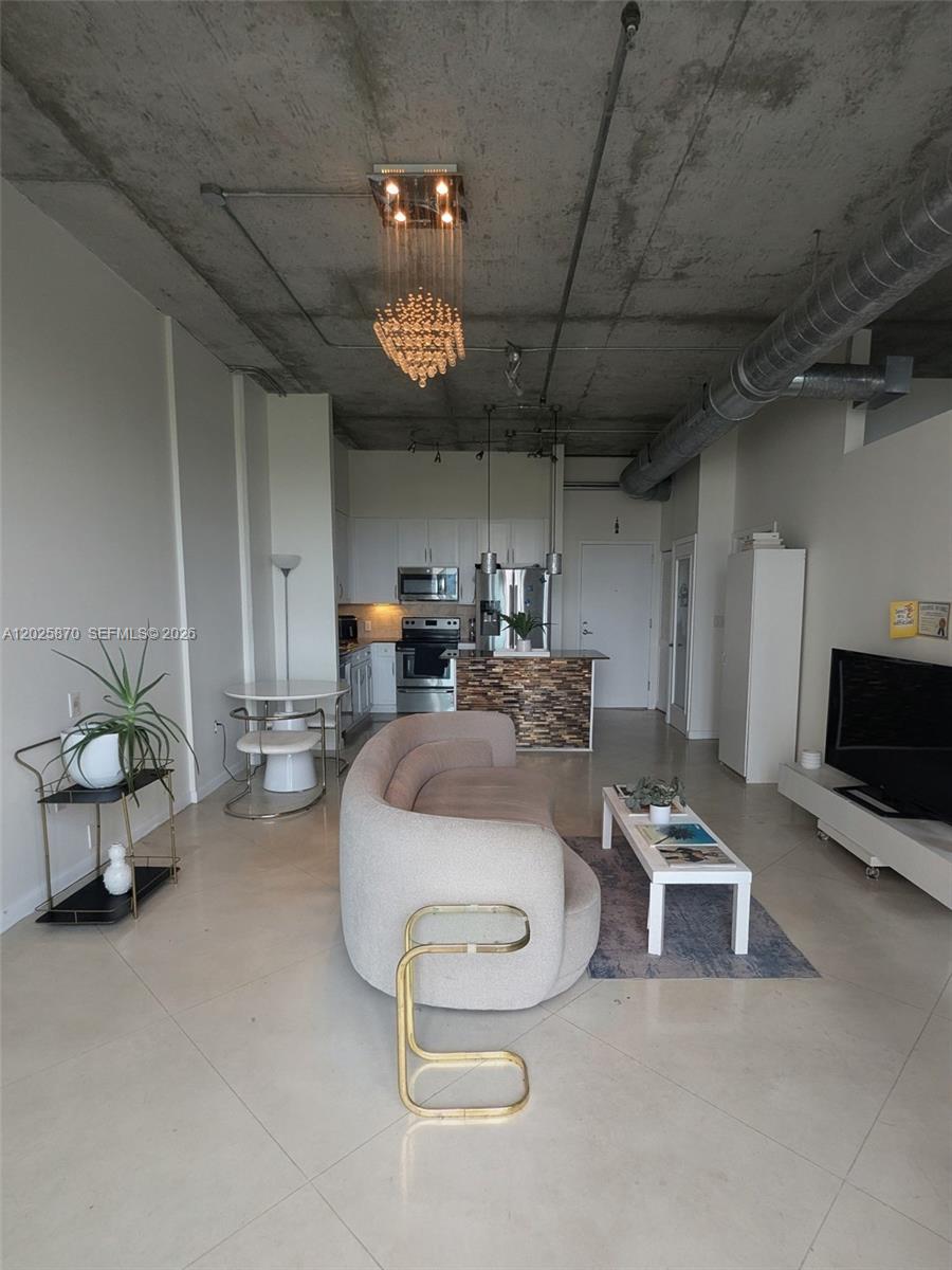 An open-concept living room and kitchen feature concrete ceilings, tile floors, and modern furniture — 2001 Biscayne Blvd # 3506, Miami FL 33137, MIAMI, FL