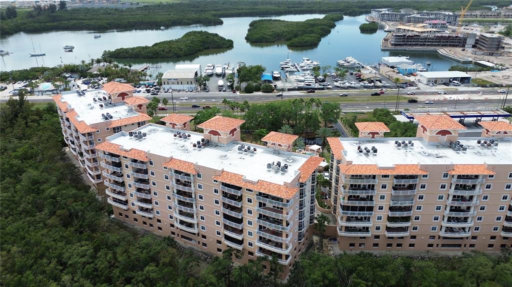 An aerial view shows multi-story tan apartment buildings with tiled roofs near a marina — 12055 GANDY BOULEVARD N UNIT 243, ST PETERSBURG, FL