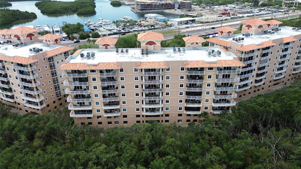 An aerial view of a multi-story apartment building with a tiled roof near water — 12055 GANDY BOULEVARD N UNIT 243, ST PETERSBURG, FL