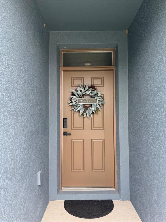 A brown front door with a wreath and transom window is set within a recessed entryway — 635 AUTUMN STREAM DRIVE, AUBURNDALE, FL