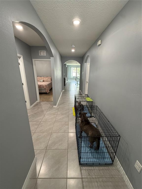 A long hallway with light gray walls and tile flooring features two dog crates — 635 AUTUMN STREAM DRIVE, AUBURNDALE, FL