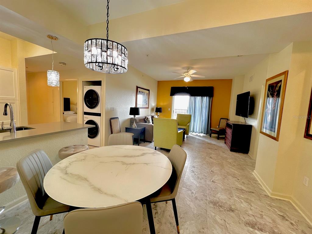 A dining area with a marble table opens into a living room with yellow walls — 8000 POINCIANA BOULEVARD UNIT 2705, ORLANDO, FL