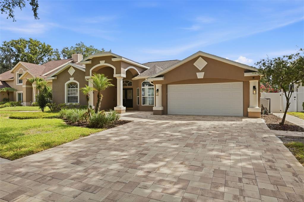 A single-story house with a tan stucco exterior, a paved driveway, and a two-car garage — 7208 YARDLEY WAY, TAMPA, FL