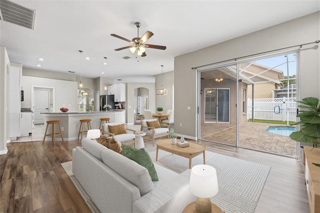 An open-concept living room and kitchen featuring light wood floors, a pool, and patio — 7208 YARDLEY WAY, TAMPA, FL