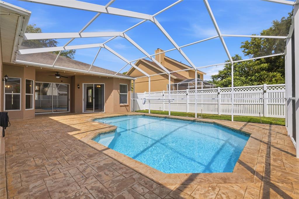 A swimming pool with a screened enclosure and stamped concrete patio behind a house — 7208 YARDLEY WAY, TAMPA, FL