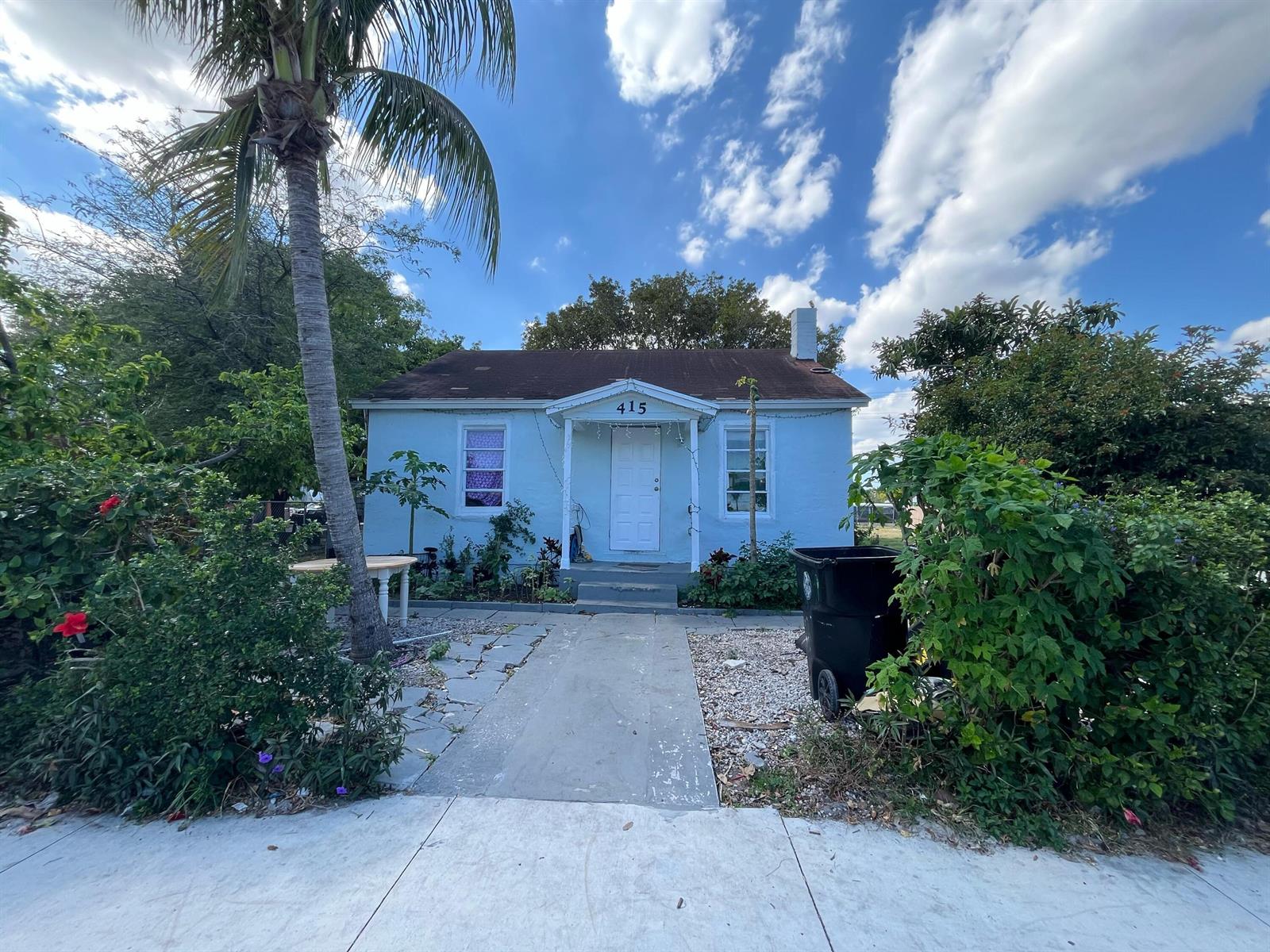 A light blue single-story house with a palm tree and a concrete walkway in front — 415 N H Street, FL 33460, FL