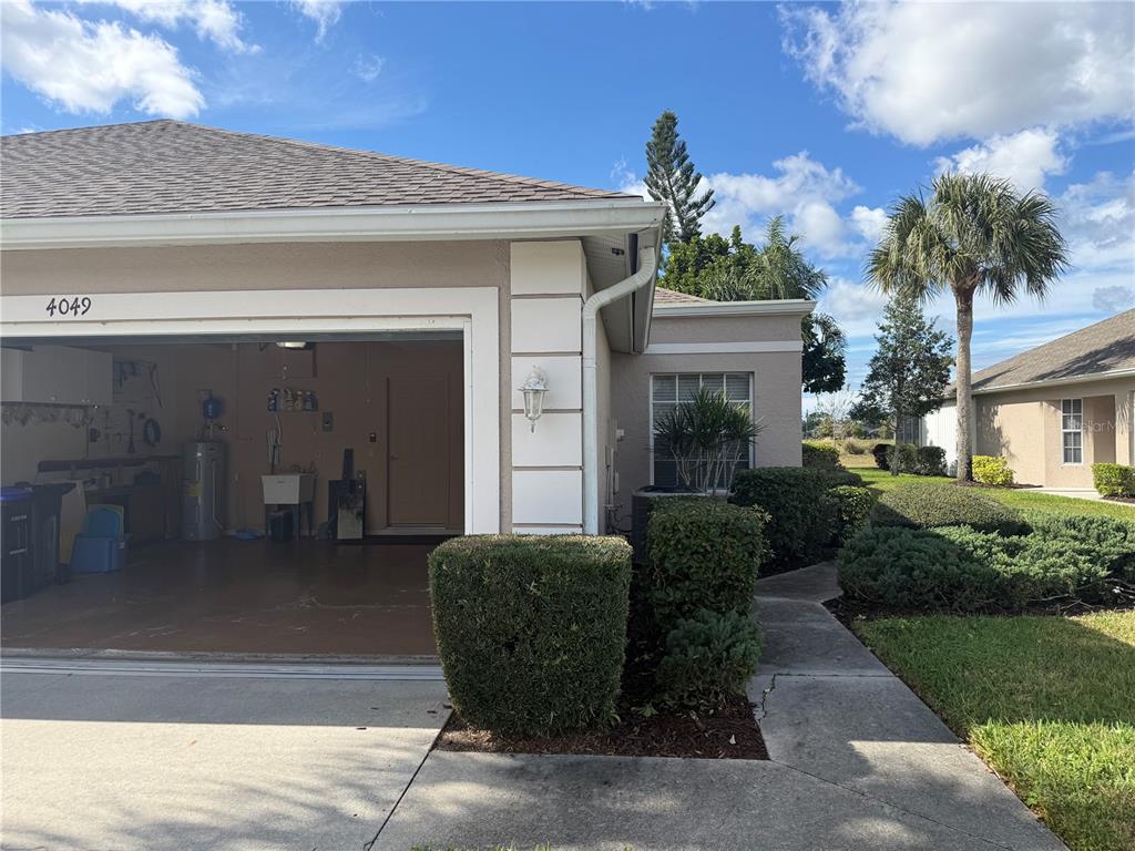 A view of a house exterior showing an open garage, landscaping, and a concrete walkway — 4049 FAIRWAY DRIVE, NORTH PORT, FL