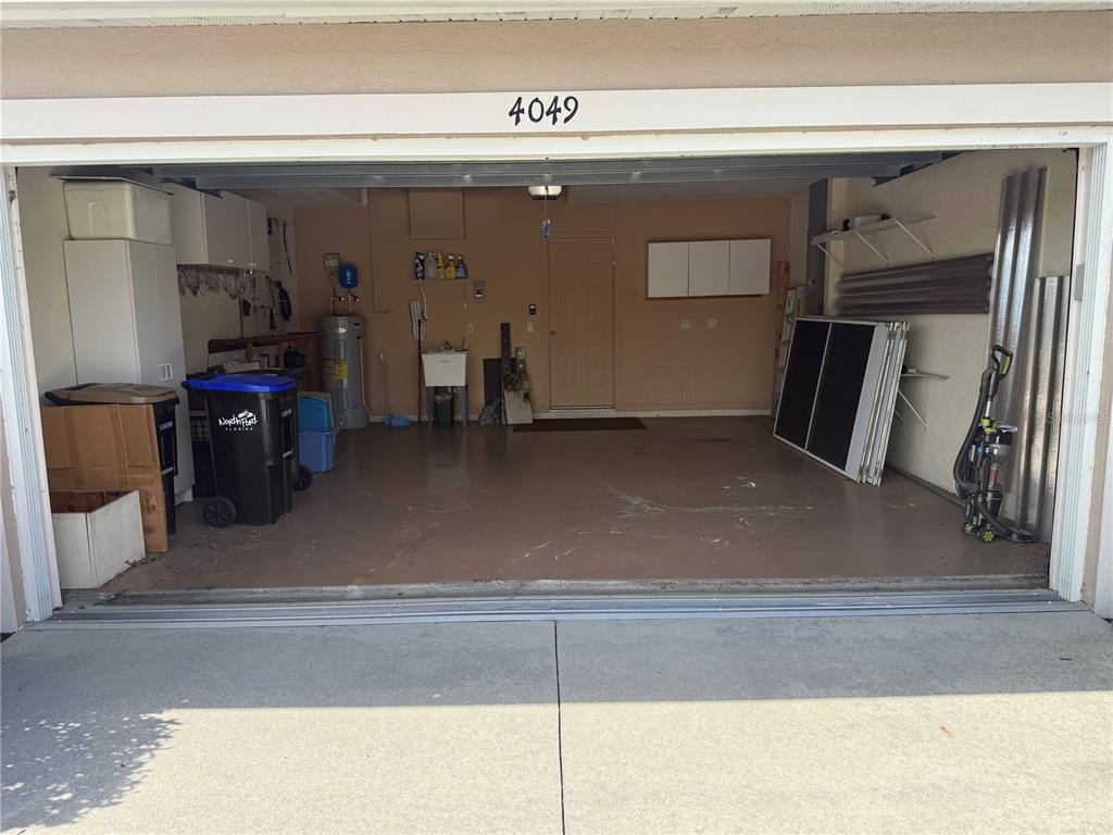 An open garage with a concrete floor, a utility sink, and various storage items — 4049 FAIRWAY DRIVE, NORTH PORT, FL