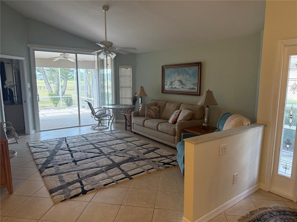 A living room features a beige sofa, a patterned area rug, and sliding glass doors — 4049 FAIRWAY DRIVE, NORTH PORT, FL