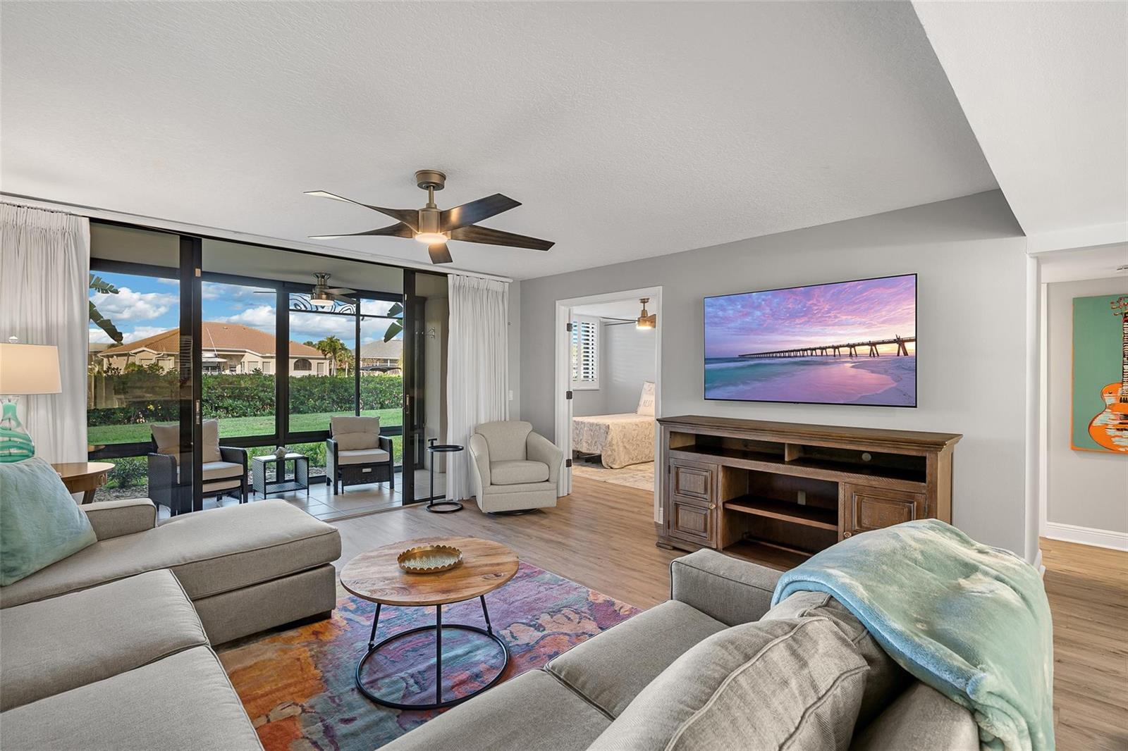 A living room features a sectional sofa, a television, and a sliding door to a lanai — 1825 Tarpon Lane # 106, Vero Beach FL 32960, VERO BEACH, FL