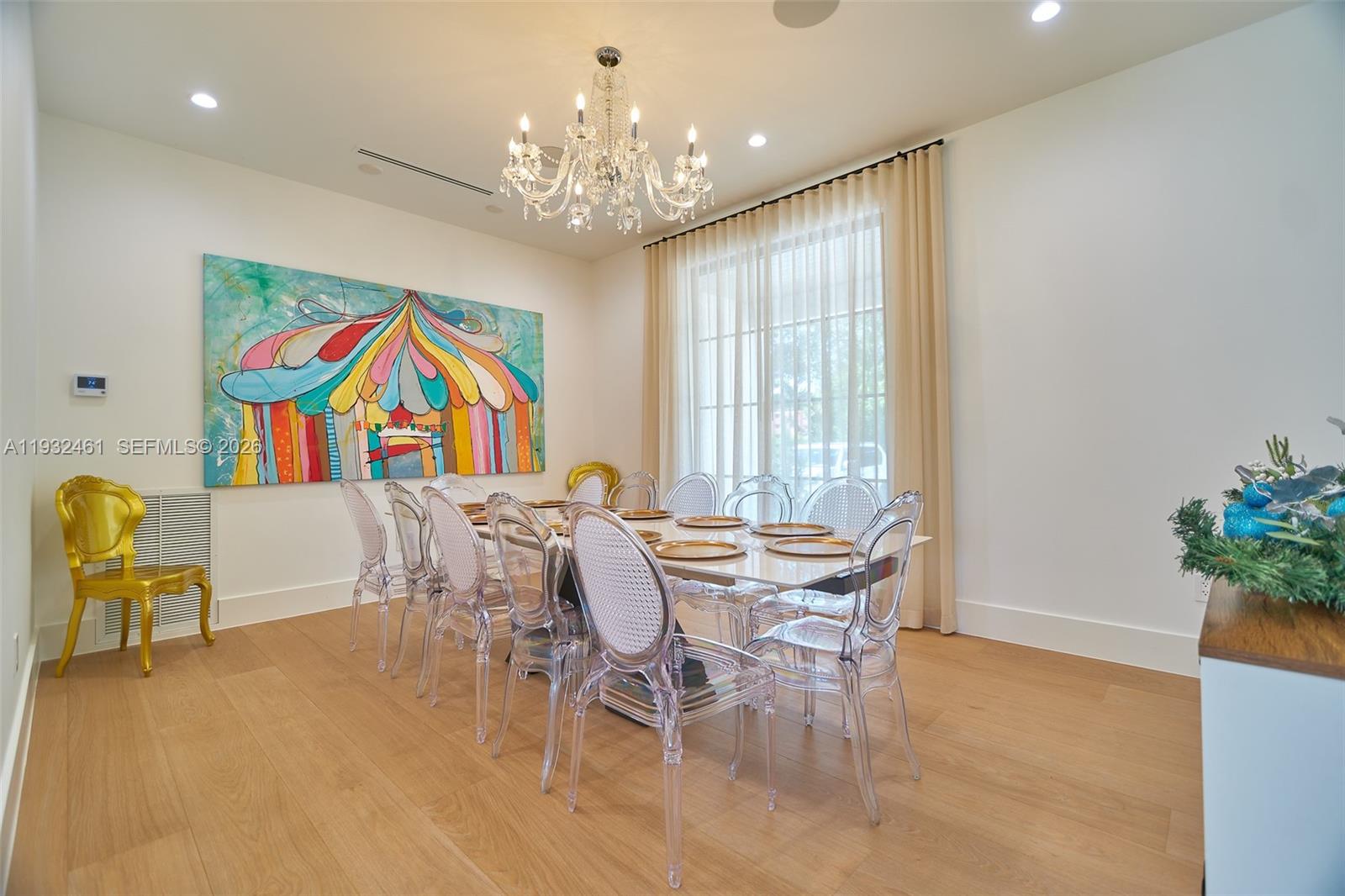A dining room features a large carousel painting, a crystal chandelier, and clear acrylic chairs — 11001 SW 74th Ave, Pinecrest FL 33156, PINECREST, FL