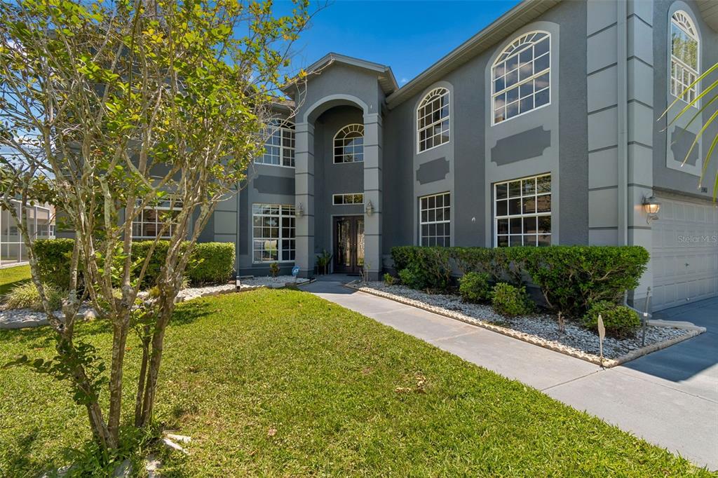 A two-story gray house with a arched entryway, white trim, and a front lawn — 15911 MUIRFIELD DRIVE, ODESSA, FL