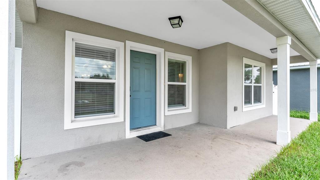A covered front porch features a blue door, two windows, and a white support column — 902 N VERMONT AVENUE, LAKELAND, FL