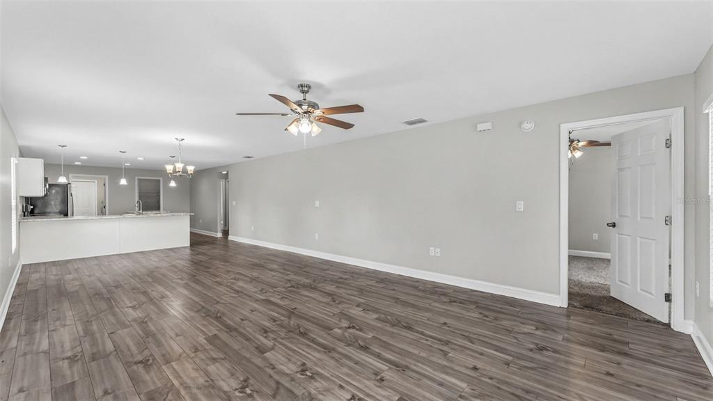 An open-concept living area features wood-look tile flooring, a ceiling fan, and a kitchen island — 902 N VERMONT AVENUE, LAKELAND, FL