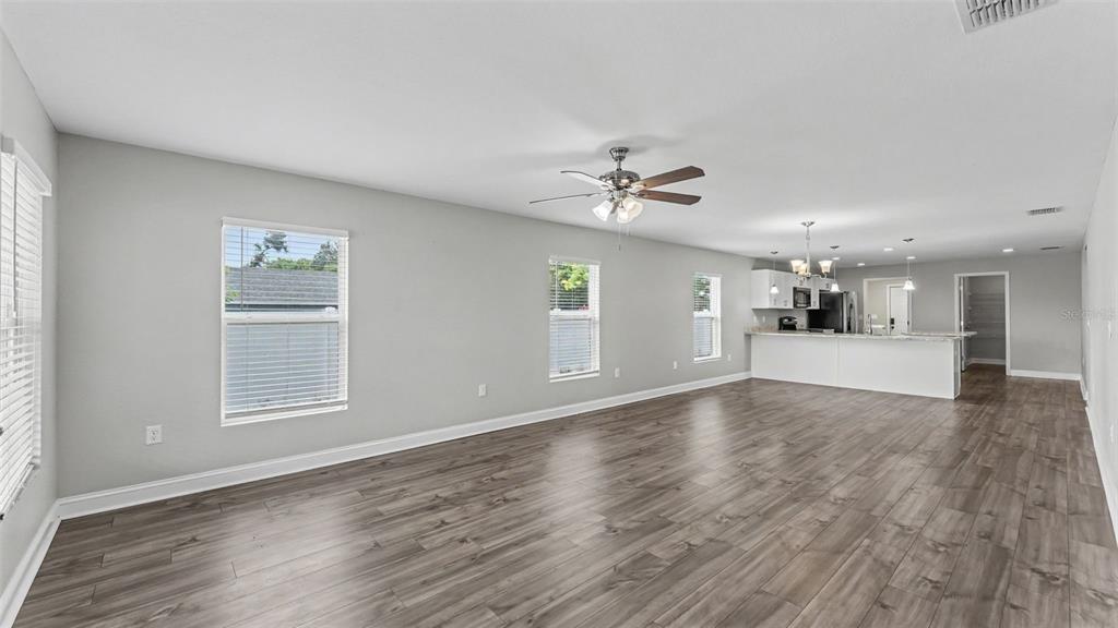 An open-concept living area features light gray walls, wood-look flooring, and a kitchen island — 902 N VERMONT AVENUE, LAKELAND, FL