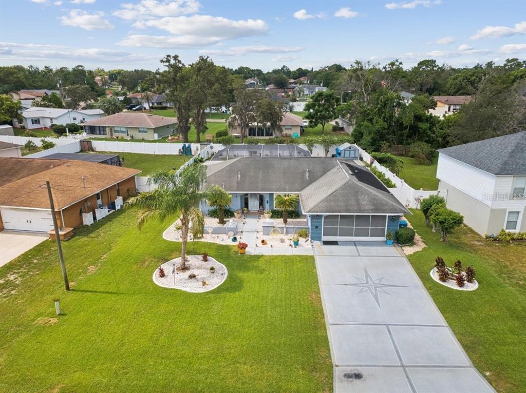 An aerial view of a single-story house with a driveway, palm tree, and fenced backyard — 13220 LINDEN DRIVE, SPRING HILL, FL