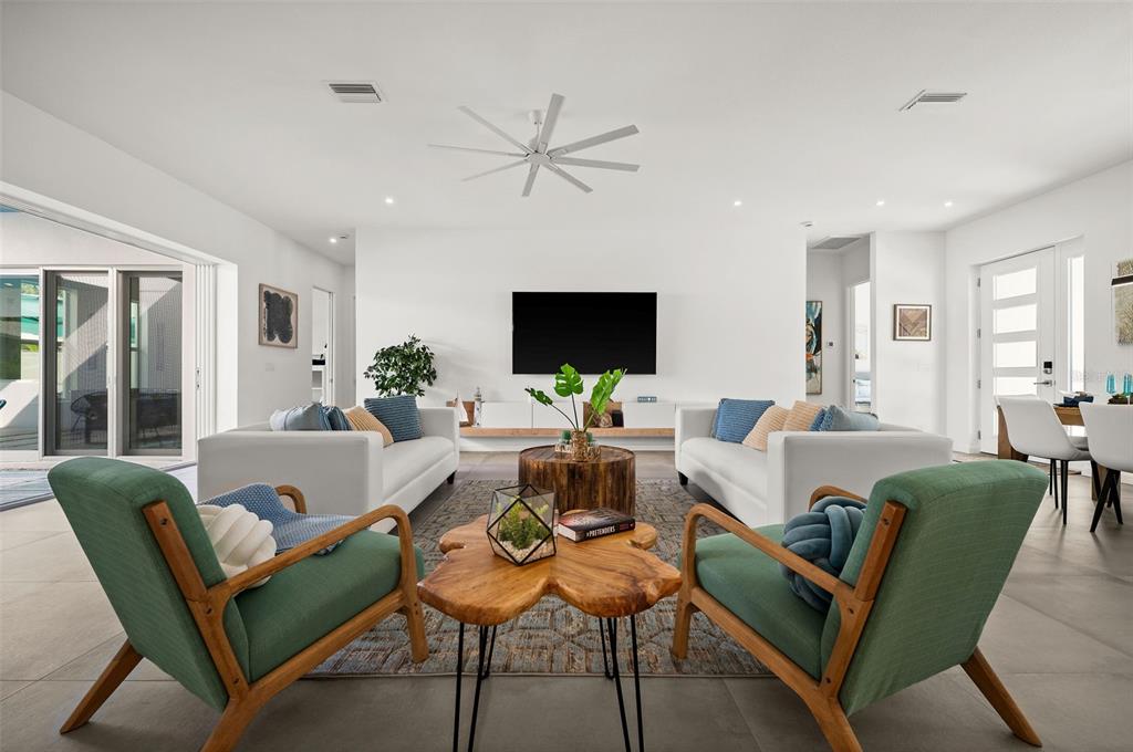 A modern living room features two white sofas, green armchairs, and wood accent tables — 2365 WALDEMERE STREET, SARASOTA, FL