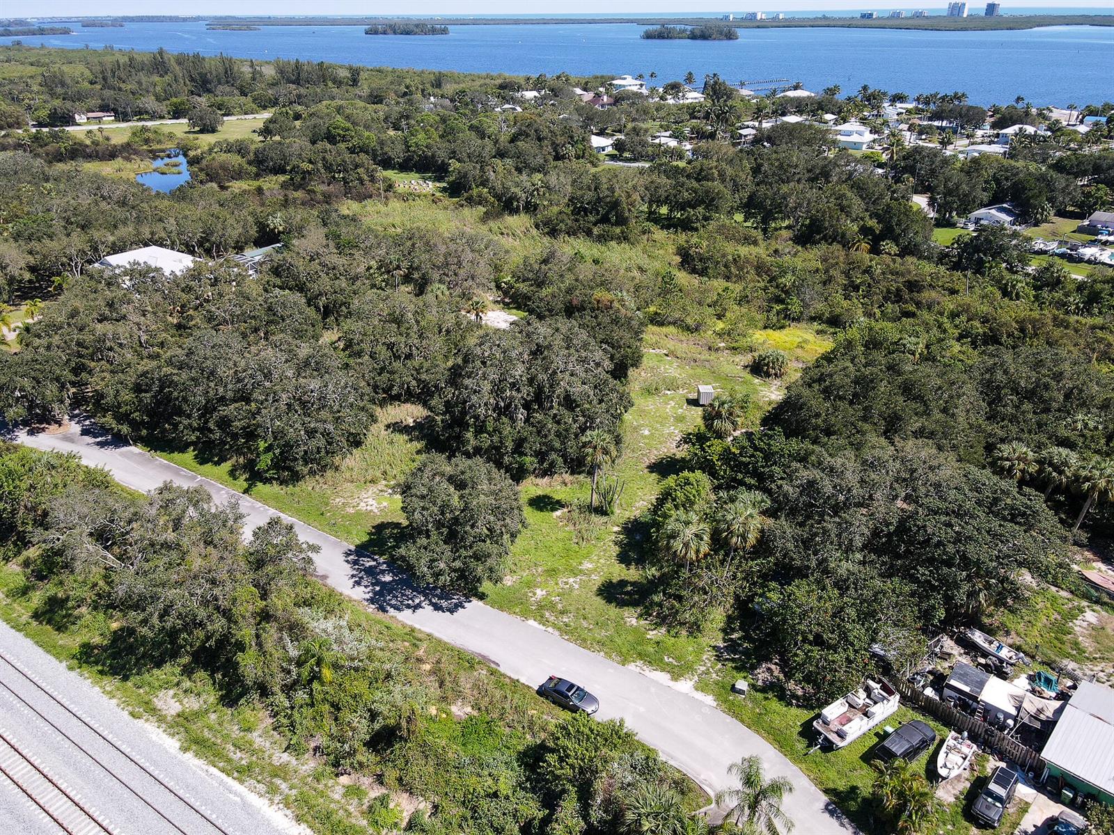 An aerial view shows a wooded lot next to a road and railroad tracks — 4108 Mariner Oaks Way, FL 34946, FL