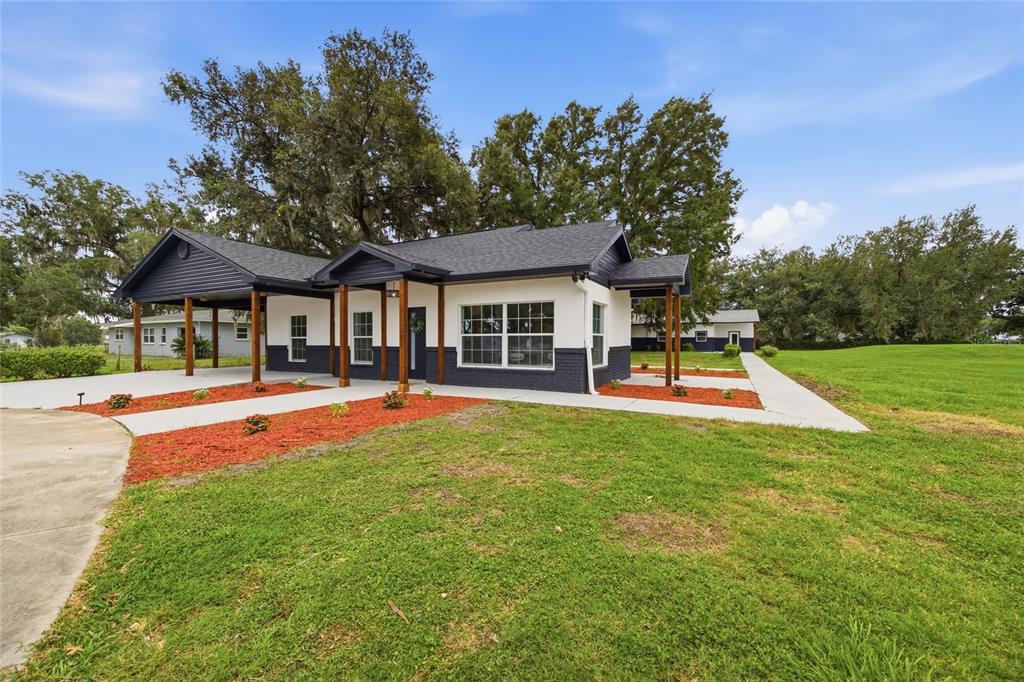 A single-story house with a white and dark gray exterior, a carport, and a walkway — 1205 E KNIGHTS GRIFFIN ROAD, PLANT CITY, FL