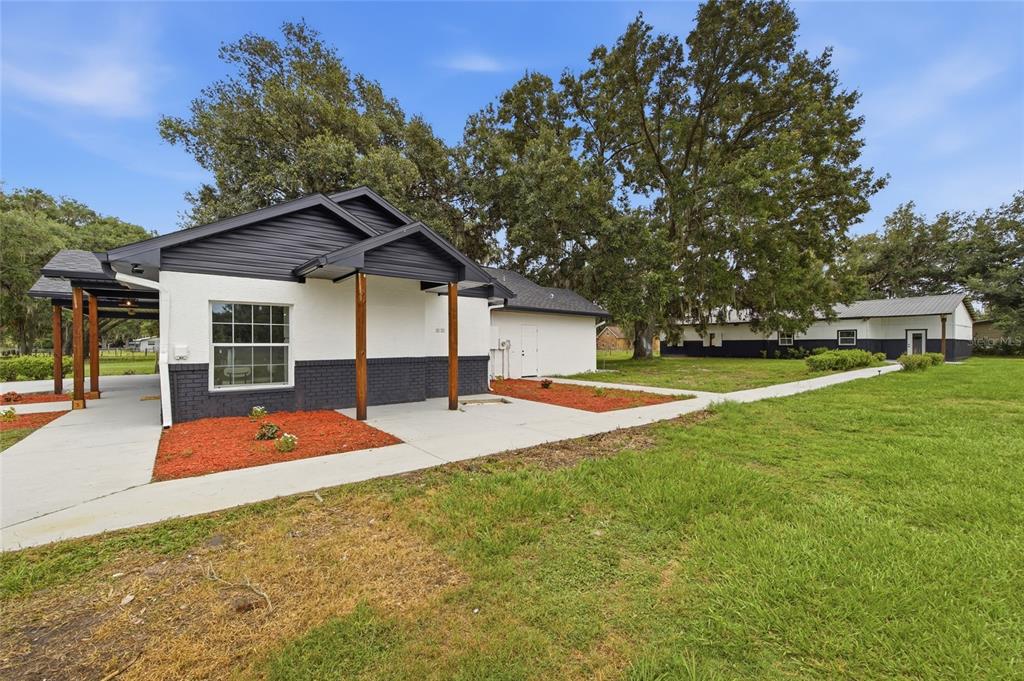 A white and black house with a covered porch and a detached building nearby — 1205 E KNIGHTS GRIFFIN ROAD, PLANT CITY, FL