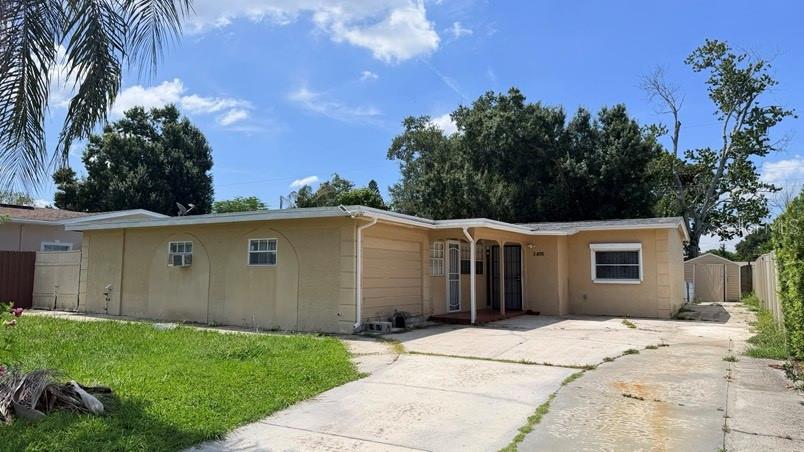A single-story tan house with a concrete driveway and a small detached shed in back — 3408 W ELLICOTT STREET, TAMPA, FL