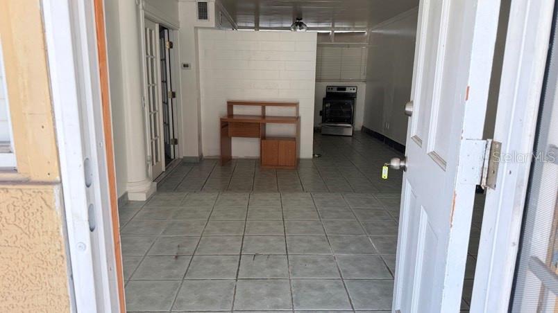 A view through an open doorway into a tiled room with a wooden desk — 3408 W ELLICOTT STREET, TAMPA, FL