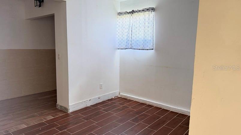 A room with white walls, a small window with patterned curtains, and dark wood-look flooring — 3408 W ELLICOTT STREET, TAMPA, FL