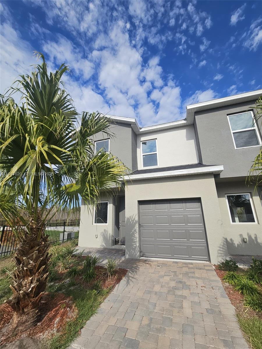 A two-story townhouse features a gray stucco exterior, a single-car garage, and a palm tree — 1201 Southstation PL # 101, Orlando FL 32809, ORLANDO, FL